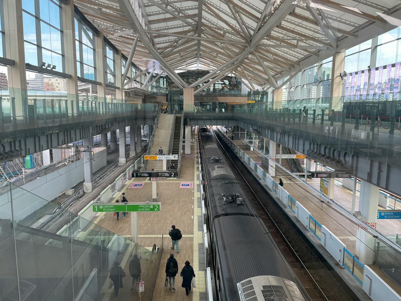 A modern Tokyo train platform with clear numbered, colour-coded platform signs