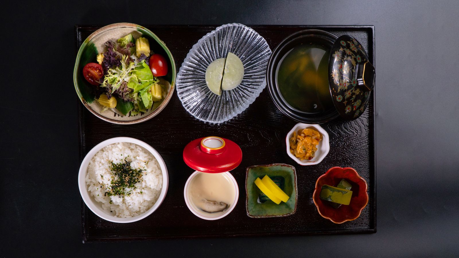 A Japanese teishoku set meal on a tray with rice, miso soup, salad, pickles and small side dishes