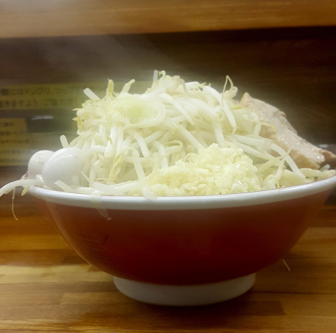 A Jiro-style ramen bowl piled with a mountain of bean sprouts and cabbage over thick noodles, fatty pork and garlic — the gut-busting style Ramen Butayama serves