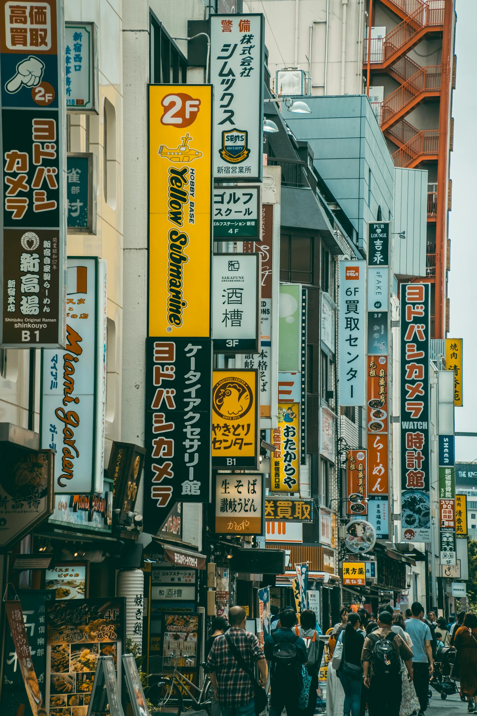 A dense, sign-covered Tokyo street near Ikebukuro packed with shops and pedestrians