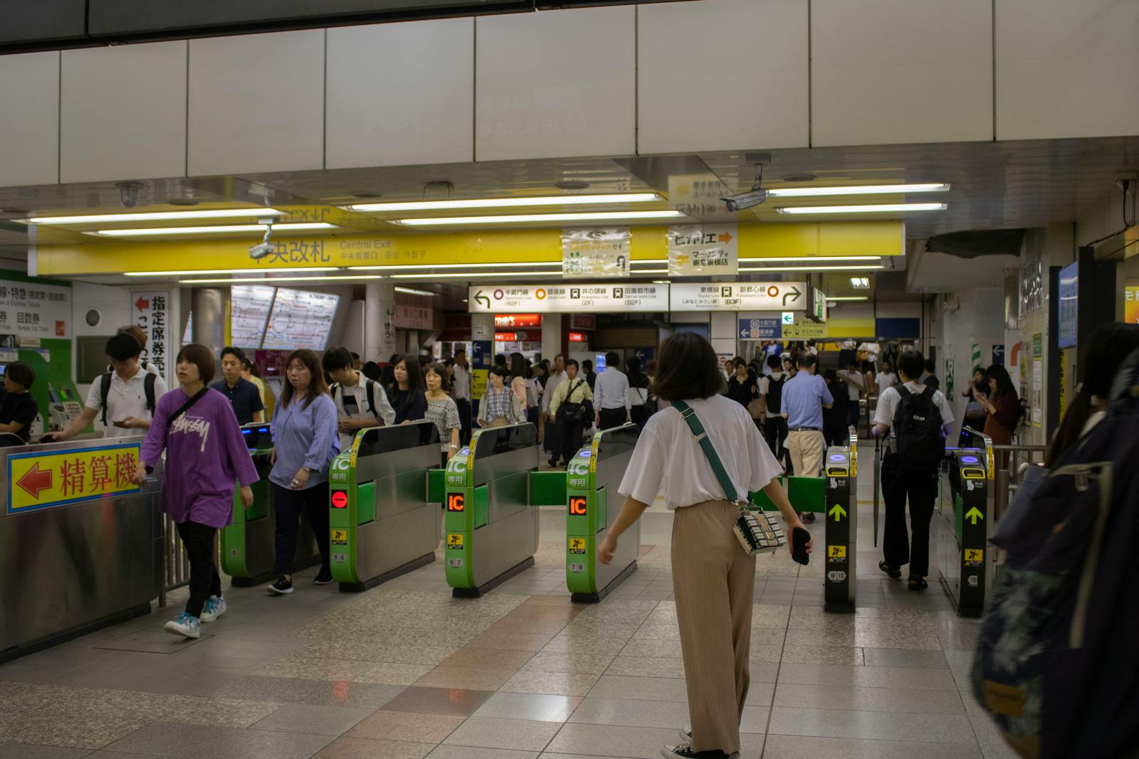 Automatic ticket gates in a Tokyo station with green IC card readers and commuters tapping through
