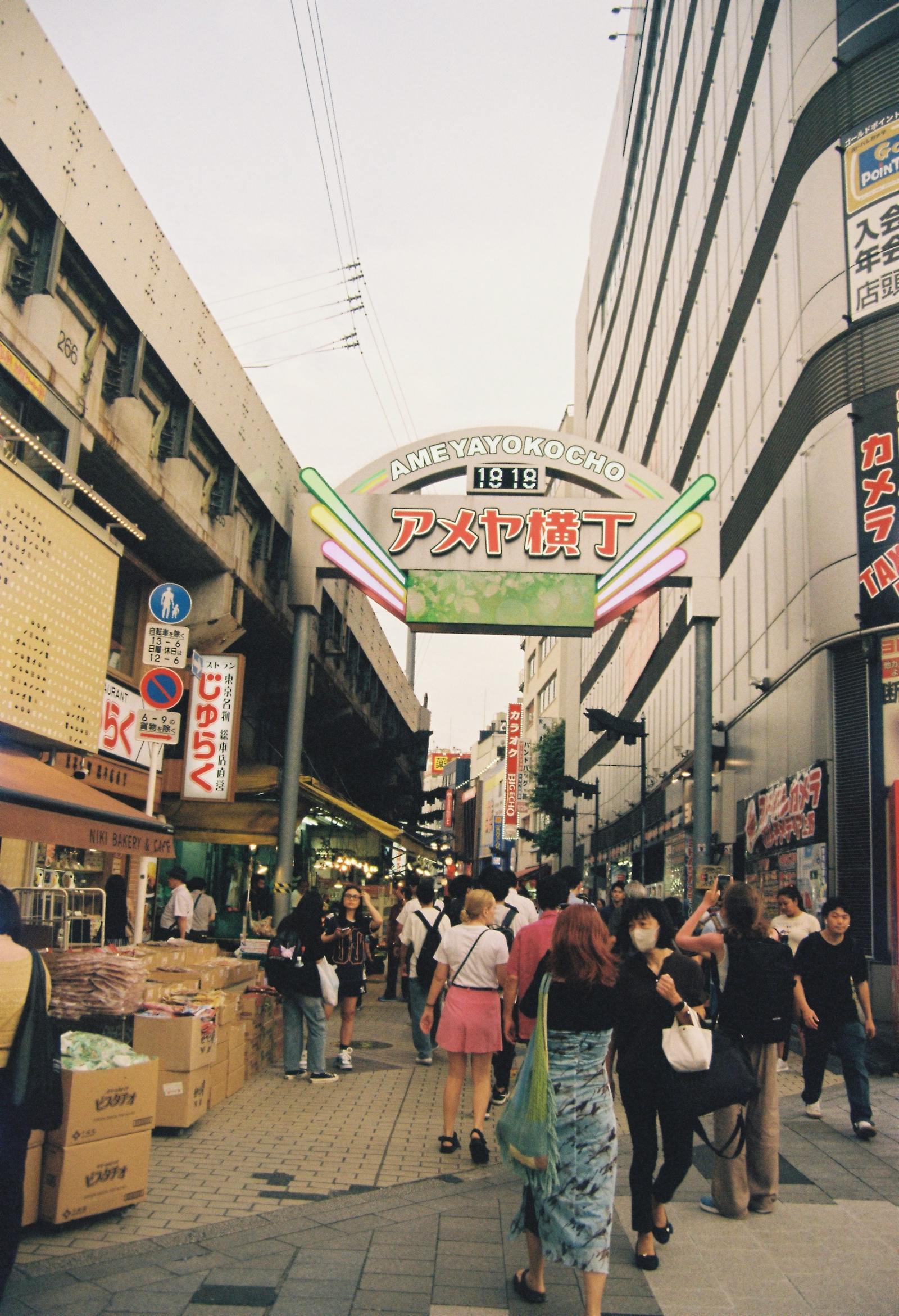 The Ameyoko market arch in Ueno with crowds shopping below the elevated train tracks